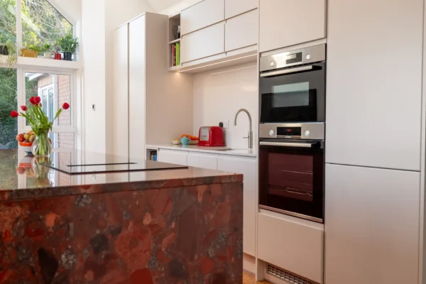 A striking red luxury kitchen with high-end taps and bespoke worktops, featuring dramatic, cathedral-like design elements.