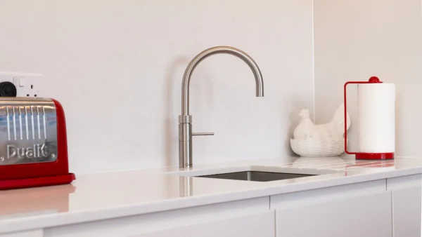 Custom-designed red kitchen with ornate detailing, brushed silver taps, and quartz worktops.