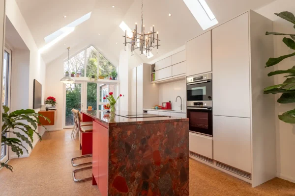 A bespoke red kitchen with intricate detailing, cathedral-style lighting, and premium fixtures.