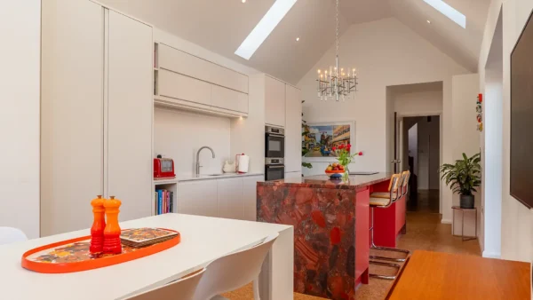 Modern red kitchen with sleek cabinetry, premium worktops, and high-end brass taps.
