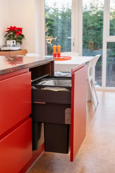 Deep red kitchen with arched windows, bespoke cabinetry, and polished stone worktops.