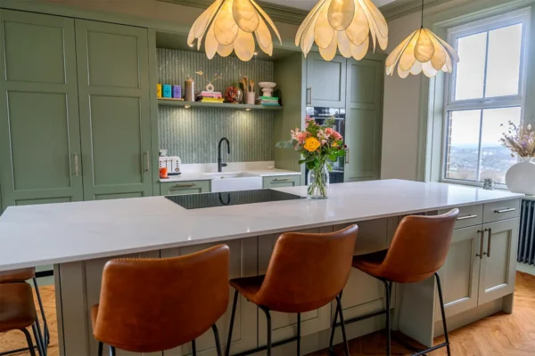 Bespoke green painted kitchen with shaker cabinetry, colour-matched Farrow & Ball tones and white quartz island worktop.