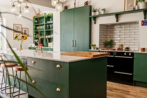 Luxury green painted kitchen with brass fixtures, open shelving and contemporary island design.